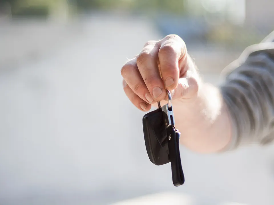 Een hand houdt een autosleutel vast, klaar voor overdracht