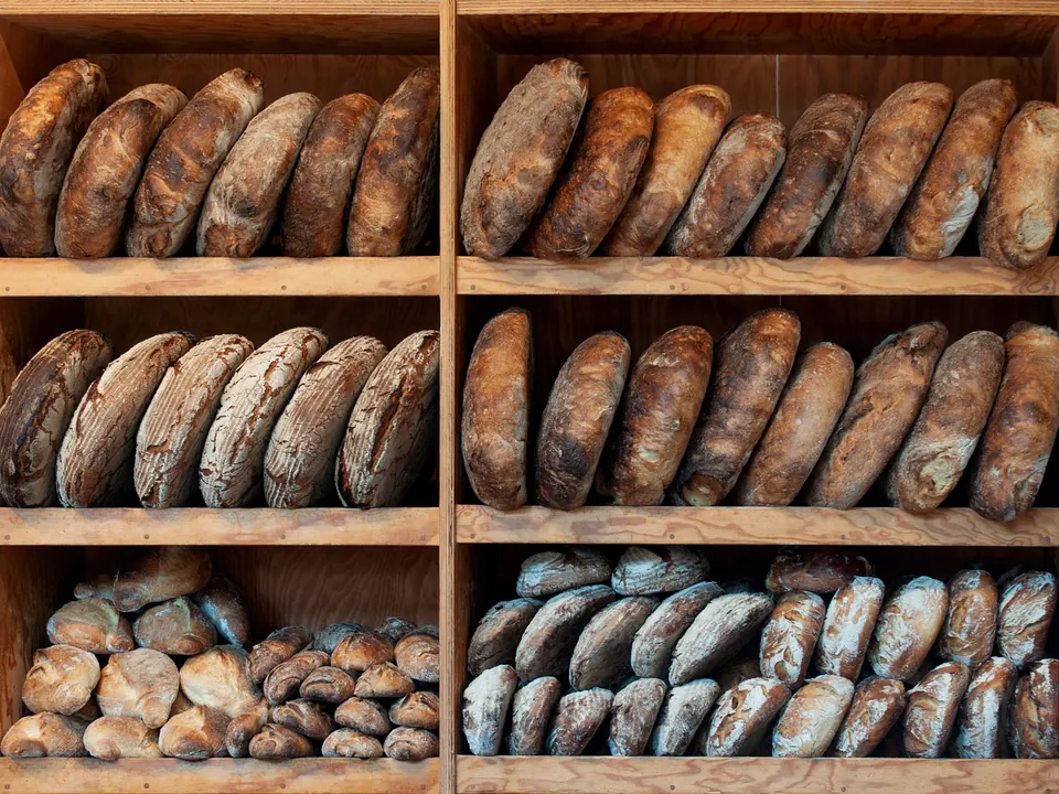 Houten schappen vol ambachtelijke broden in een bakkerij