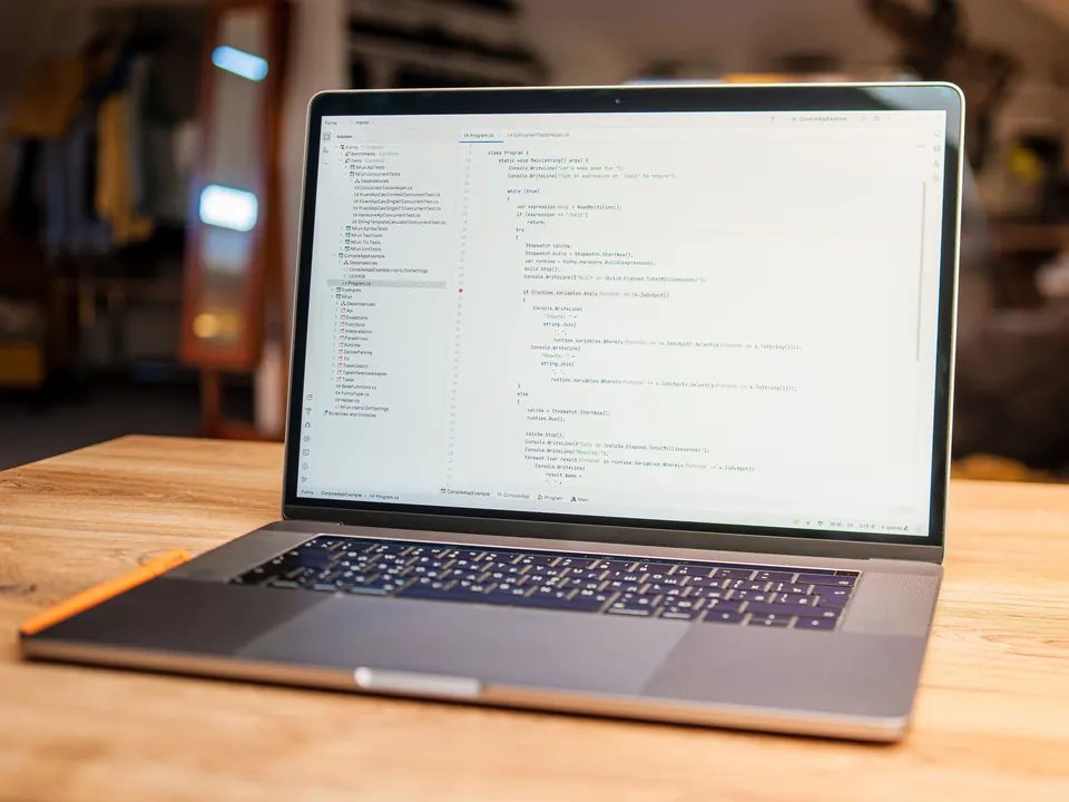 Open laptop met programmeercode op het scherm, op een houten bureau