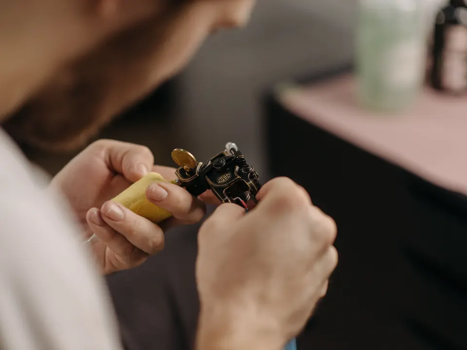 Tattoo-artiest stelt zijn tattoomachine bij, met alleen de handen en de machine scherp in beeld